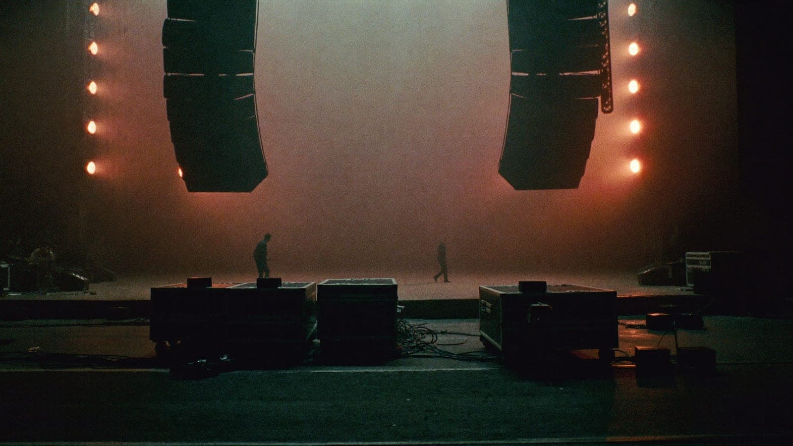 A wide show floor with line arrays and warm rig lights, set shortly before doors open